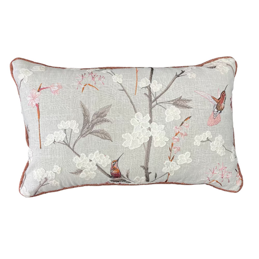 Decorative pillow with floral and bird design on a wooden surface
