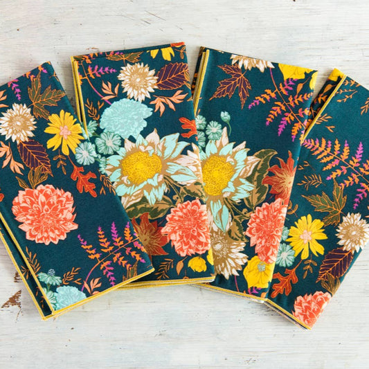 Set of four floral-patterned notebooks on a wooden surface
