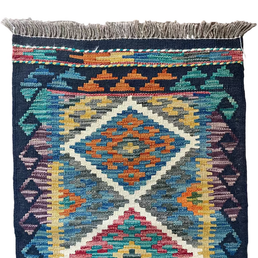 Multicolored patterned rug with fringes on a wooden floor